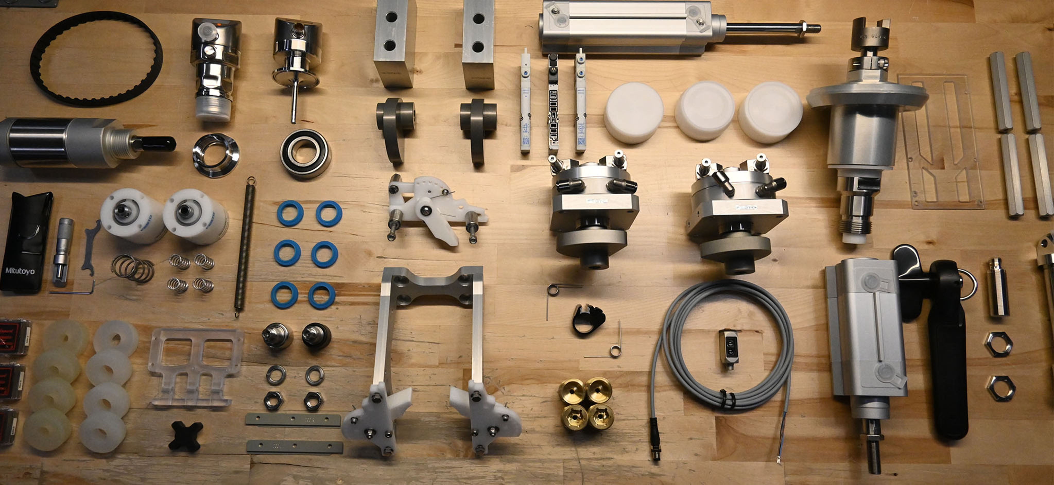 An assortment of parts methodically placed on a wooden work table.