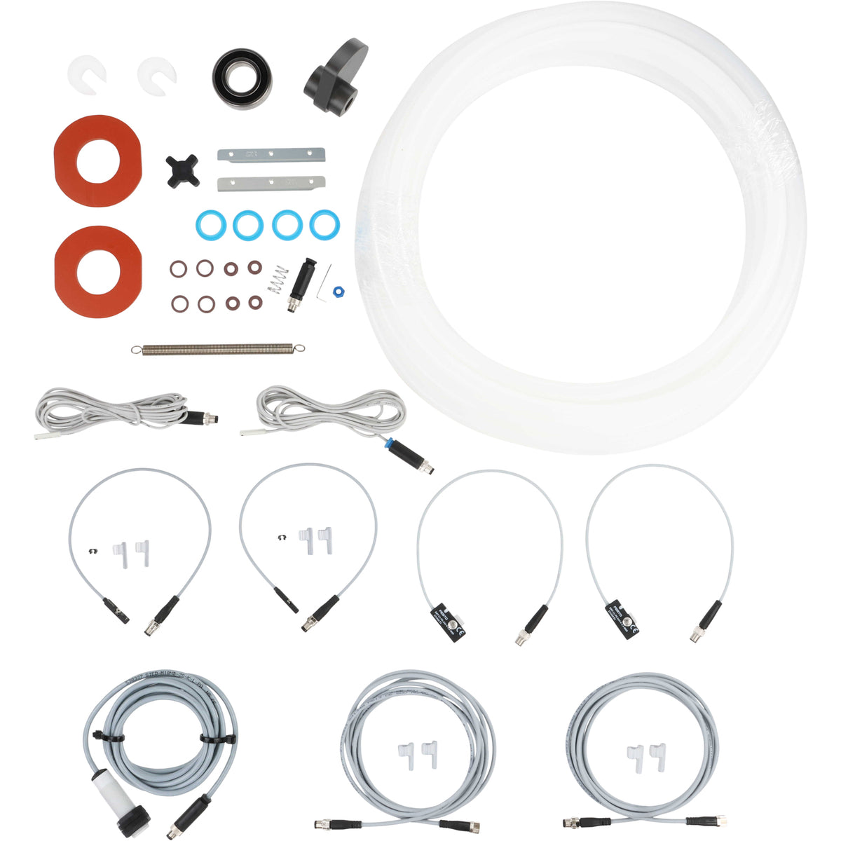 An assortment of parts that include CP Stop Blocks (5/16&quot;), Puck Bearing, Rotary Cam, CP Seals (Quick Release), Rubber Coupling Spider, Lid Knives, Rod Seals, Tip of Actuator Rod O-Rings, Gland Retainer O-Rings, Seamer Plunger Spring, Male M8 Quick Connects, Seamer Swing Arm Spring, 25ft of product tubing, Seam Rotary Sensors, Lid Drop and Seam Lift Sensors, Inductive Sensor,  and 2.5m Sensor Cables.  All parts are shown on a white background. 